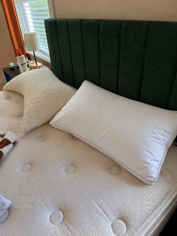 Review photo: the pillow on a mattress in front of a green velvet headboard