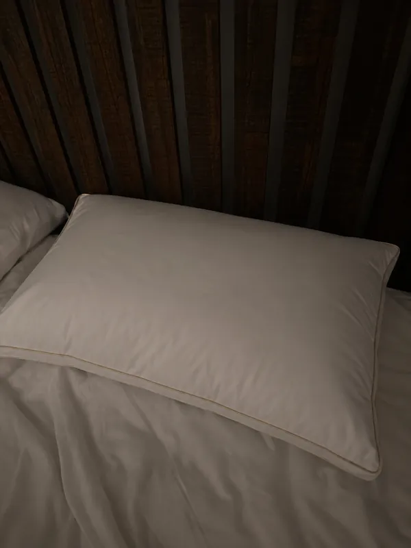 Review photo: the pillow on a bed against a dark slatted headboard